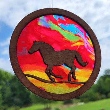 Circular, wooden suncatcher with a horse running. Transparent acrylic background with multi colored "fire".