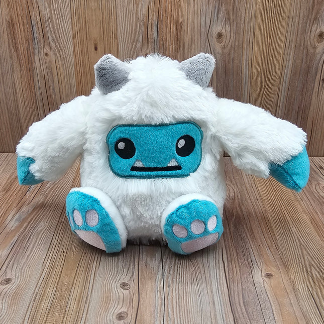 Front view of a plush yeti stuffed animal with white fur, gray horns, and blue hands, feet, & face