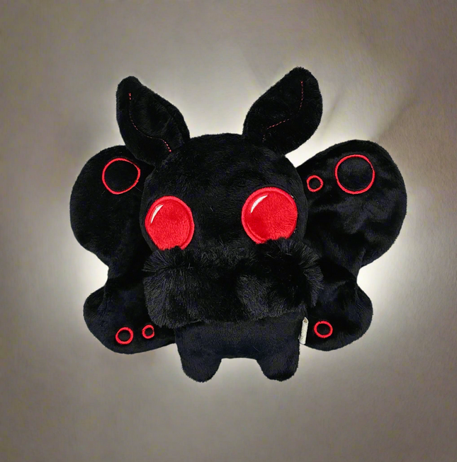 image of plush mothman on a light backgound with bright light behind