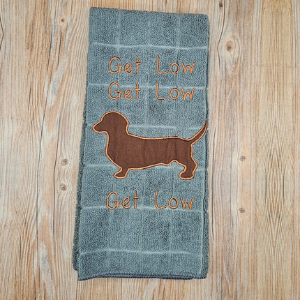 image of a gray embroidered polyester kitchen towel. It says "Get Low" 3 times and has a brown dachshund silhouette 