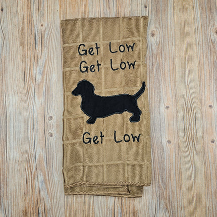 image of a tan embroidered polyester kitchen towel. It says "Get Low" 3 times and has a black dachshund silhouette 