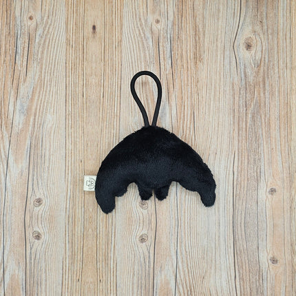 Back view of black plush mothman toy. Black loop for travel or display from a bag