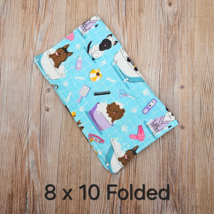 image of folded 8x10 flannel towel with dogs in the bath and grooming supplies  on a light blue background