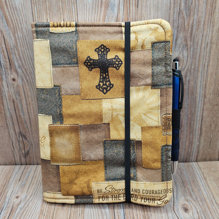 Patchwork-style notebook with cross design on a wooden surface