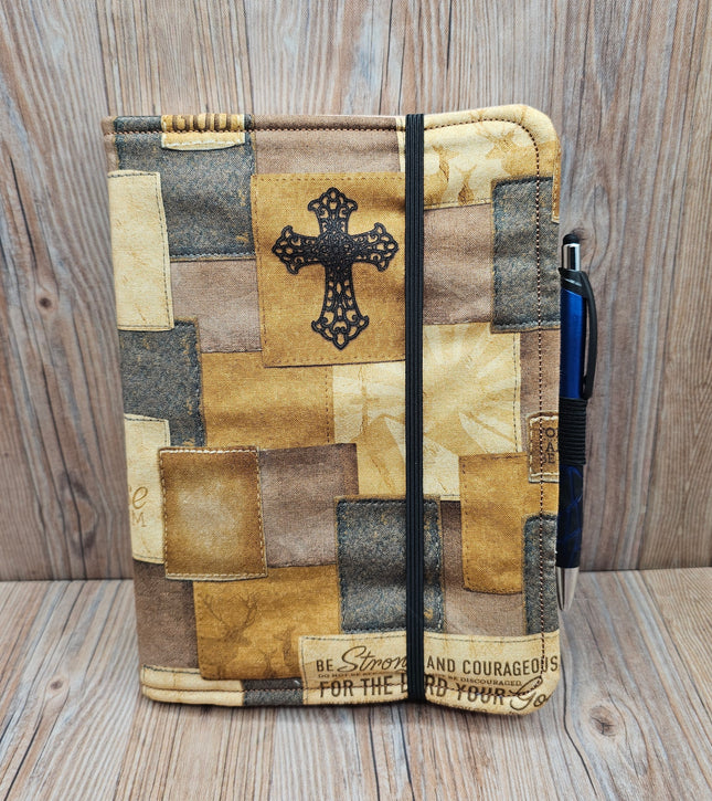 Patchwork-style notebook with cross design on a wooden surface