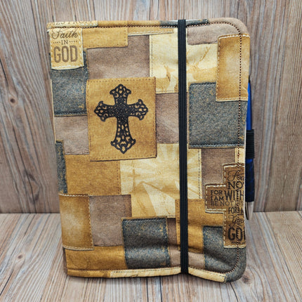 Patchwork-style notebook with cross design on a wooden surface