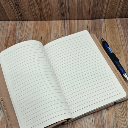 Open notebook with lined pages on a wooden surface, accompanied by a pen.