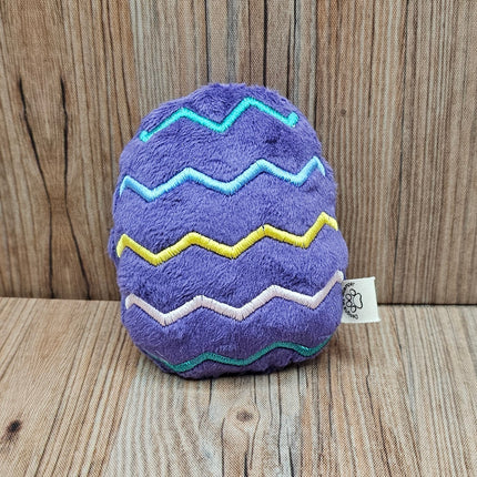 Purple easter egg plush cat toy with zigzag patterns on a wooden surface