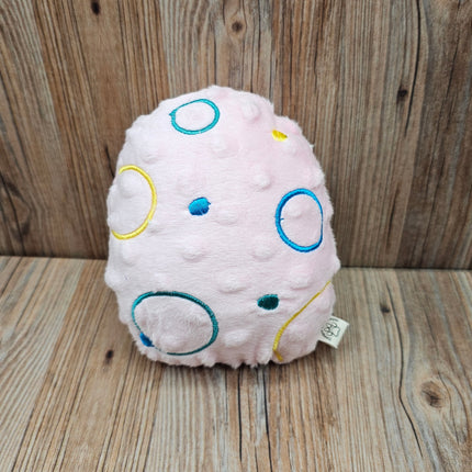 Pink plush easter egg dog toy with embroidered circle design