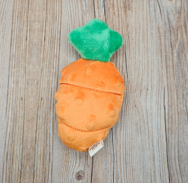 Plush carrot cat toy with a green top on a wooden surface
