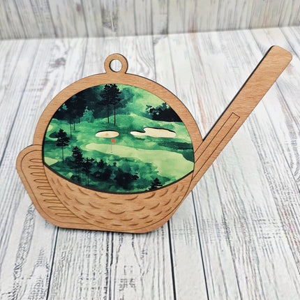 transparent acrylic suncatcher with a golf theme. Suncatcher has a wooden top layer that is in the shape of a golf club and ball. Details are laser etched. image shows close up of suncatcher without natural light