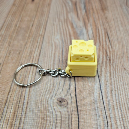 Yellow keychain shaped like a block of cheese on a wooden surface