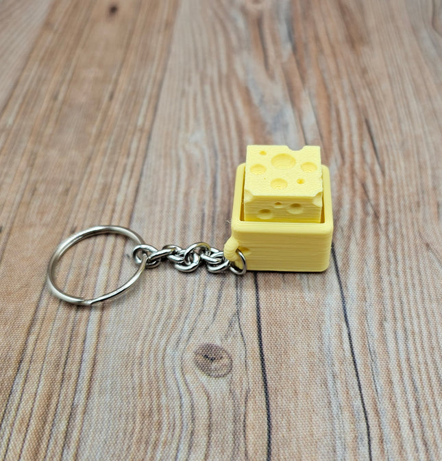 Yellow keychain shaped like a block of cheese on a wooden surface