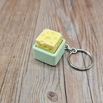 Cheese-shaped keychain with a mint green base on a wooden surface