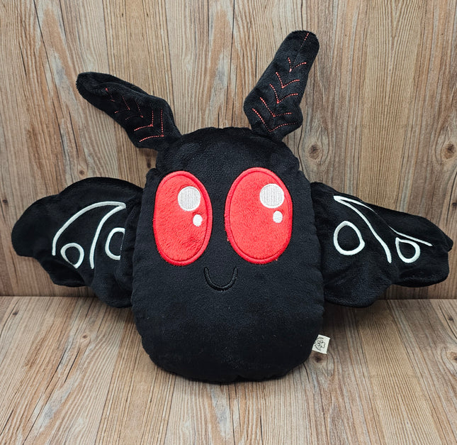 Handmade mothman plush made from black minky fabric, featuring red embroidered eyes and outstretched wings.