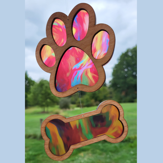 image of a wooden suncatcher with a transparent acrylic background. The top suncatcher is in the shape of a paw and there is a smaller suncatcher in the shape of a bone hanging beneath it. This variety is called "fire"