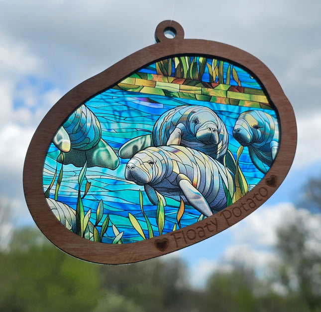 Transparent acrylic "Stained glass" manatee scene in a wooden frame with 'Floaty Potato' laser etched at the bottom.
